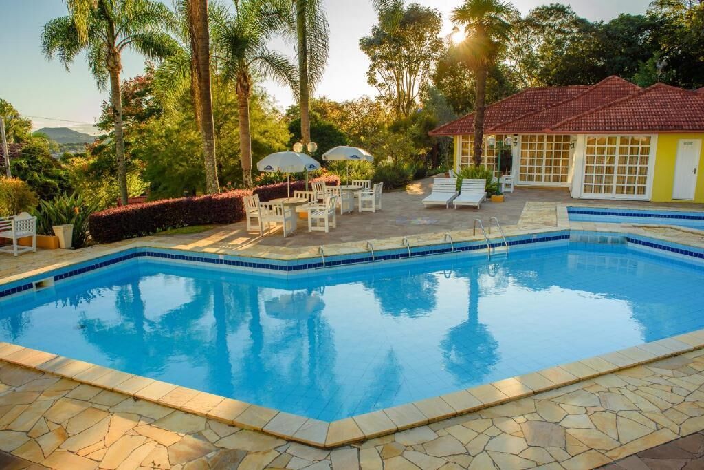 Una piscina al aire libre, sombrillas, sillones reclinables de piscina