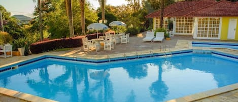 Una piscina al aire libre, sombrillas, tumbonas