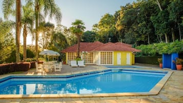 Una piscina al aire libre, sombrillas, sillones reclinables de piscina