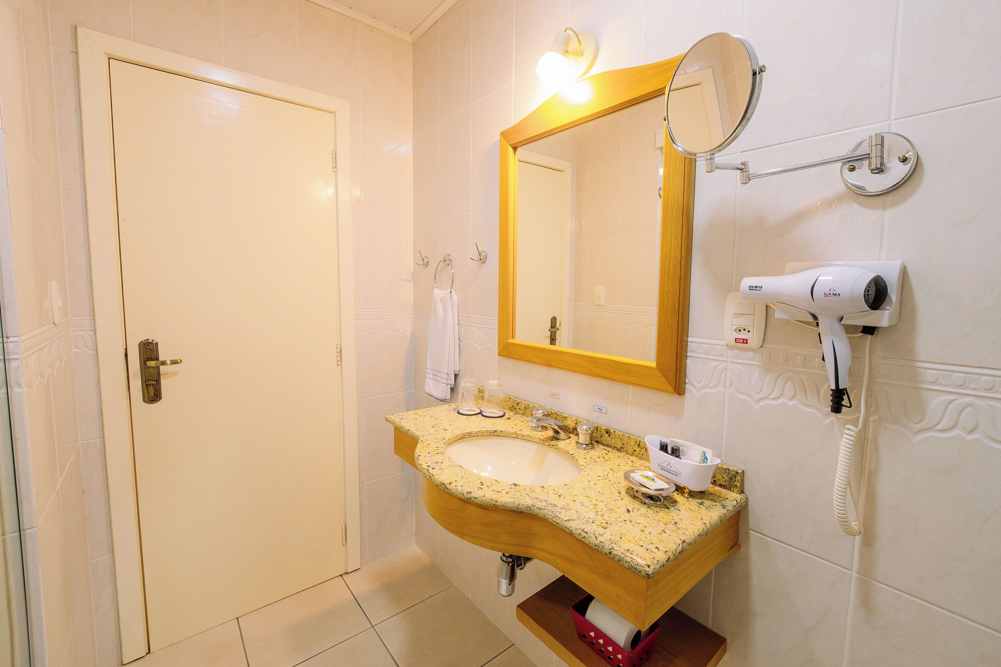 Une salle de bain équipée d’un lavabo, d’un miroir, d’un porte-serviettes et d’un sèche-cheveux.