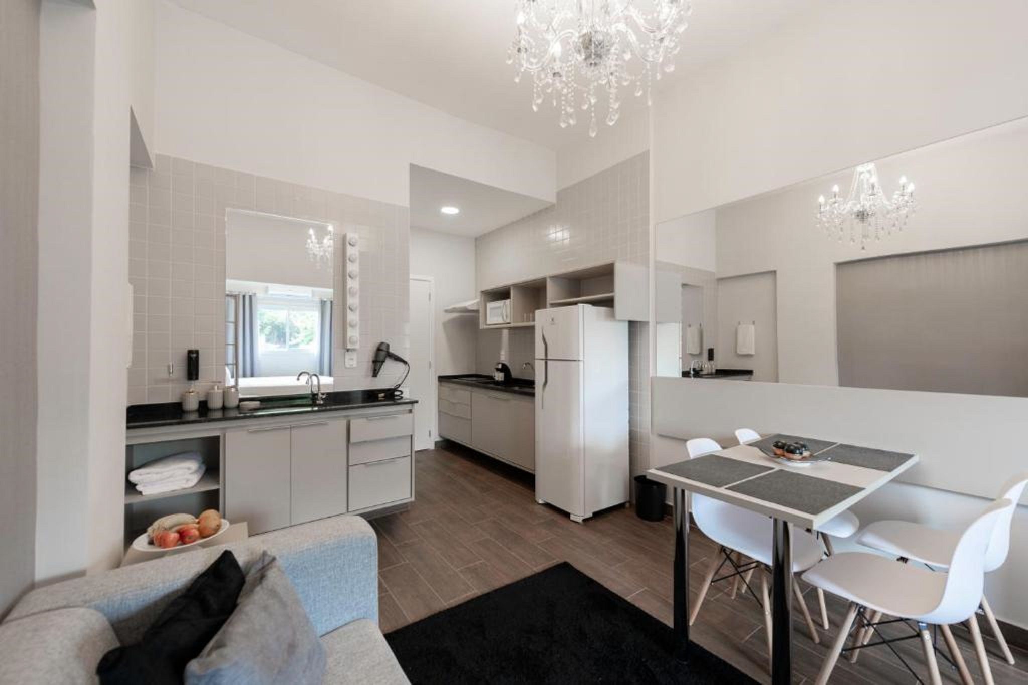 Una cocina moderna con armarios blancos, una zona de comedor con mesa y sillas, y un candelabro.