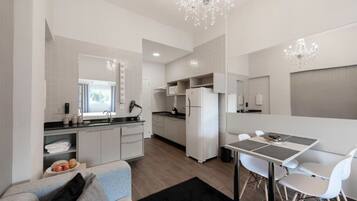 Una cocina moderna con armarios blancos, una zona de comedor con mesa y sillas, y un candelabro.