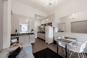 Une cuisine moderne avec des meubles blancs, un coin repas comprenant une table et des chaises, et un lustre.