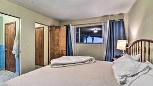 A neatly made bed with a white comforter and pillows, a wooden headboard, a window with curtains, and a lamp on the nightstand. - Lakefront Forestville Paradise w/ Private Beach! (Forestville)