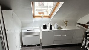 A compact kitchen with a built-in oven, a coffee maker, and a small window. - Charming, neat and bright studio, in a lively area, 15 minutes from the Louvre (Paris)