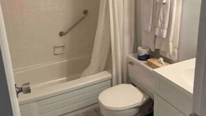 Une salle de bain avec une baignoire, des toilettes et un rideau de douche.
