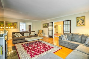 A spacious living room with a red patterned rug, two sofas, a coffee table, and a bookshelf.