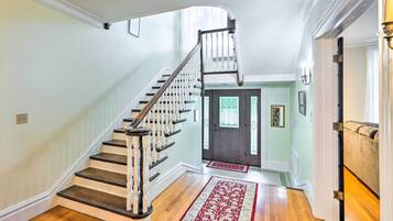 Un escalier avec des balustrades blanches et des marches sombres menant à une porte ornée de panneaux de verre décoratifs.