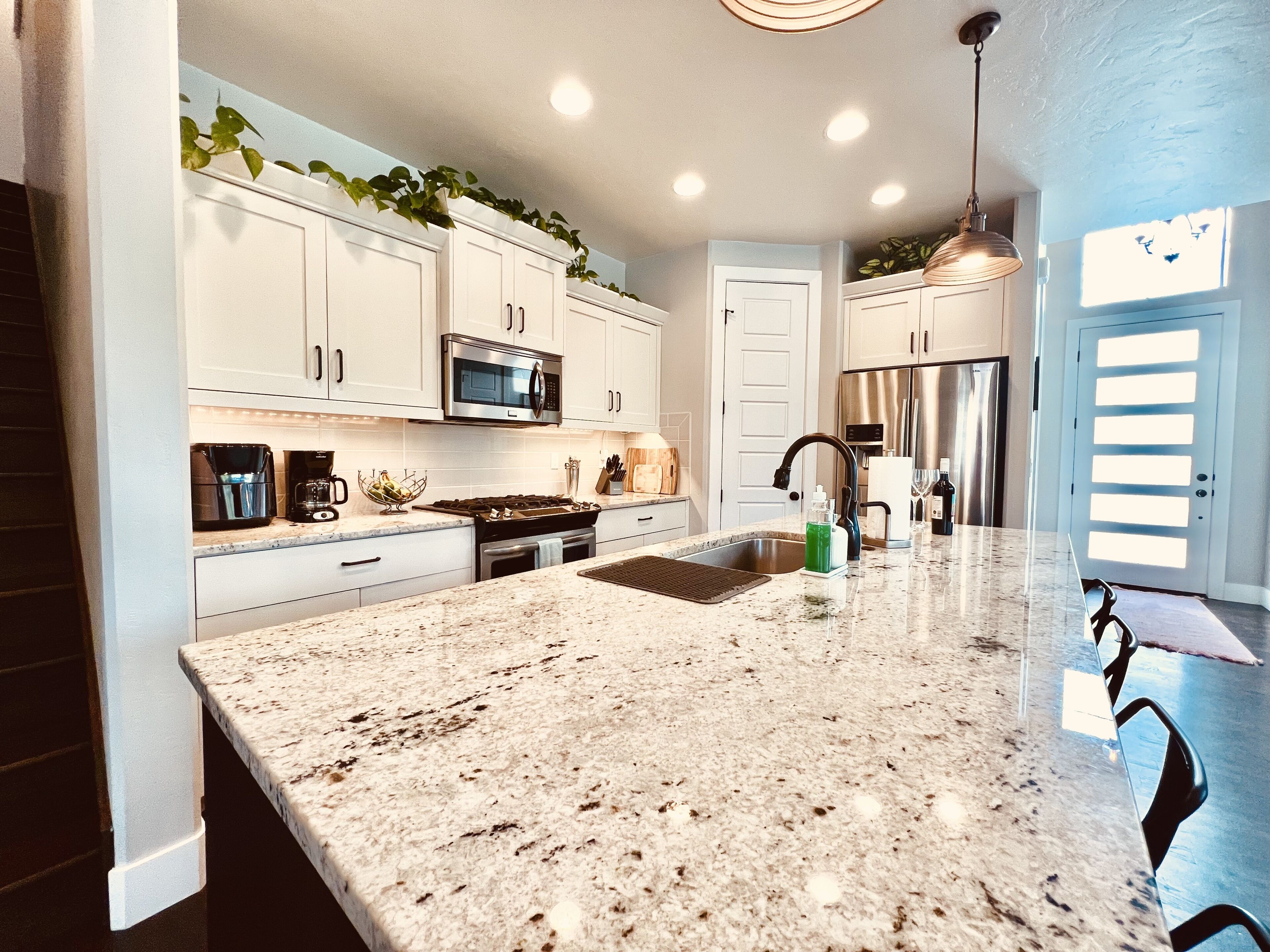A modern kitchen with white cabinets, stainless steel appliances, and a granite countertop.