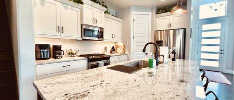 A modern kitchen with white cabinets, stainless steel appliances, and a granite countertop.