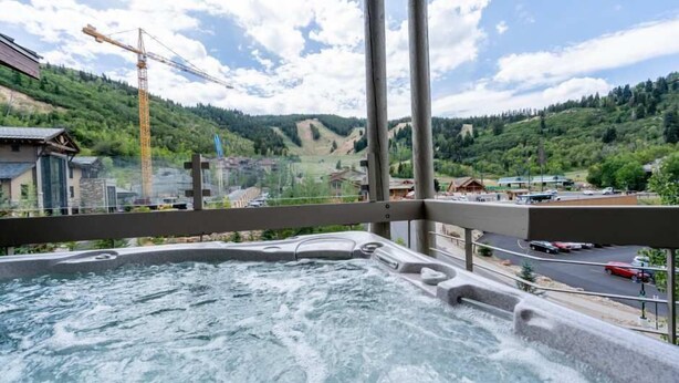 A hot tub with a view of a mountainous landscape and a construction crane in the background. - Powder Run by Park City Vacations (Park City)