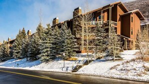 A modern lodge with a stone facade, multiple balconies, and a snow-covered landscape. - Powder Run by Park City Vacations (Park City)