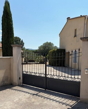 A gated entrance with a tall tree and a building in the background.