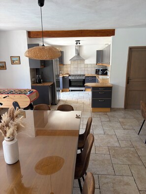 A modern kitchen with a central island, wooden flooring, and a dining area with a wooden table and chairs.