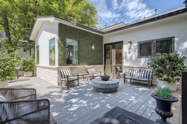 Relax in the serene outdoor patio surrounded by lush greenery and comfortable seating.