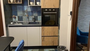 A compact kitchen with wooden cabinets, a built-in oven, and a sink. - Suite Ursino B&B (Catania)