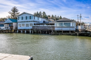 A waterfront property with multiple buildings, including a house with a balcony and a dock extending into the water.