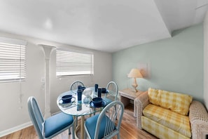 A dining area with a round table, chairs, and a small side table with a lamp. - The Cozy Deal, Washer and Dryer, Central, Budget Friendly (Jacksonville)
