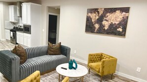 Un soggiorno con un divano grigio, due poltrone gialle, un tavolino rotondo e un'opera d'arte raffigurante una mappa del mondo appesa al muro.