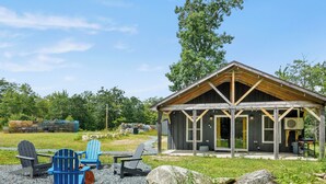 Eine rustikale Holzhütte mit überdachter Veranda, Gartenmöbeln und Kiesfläche.