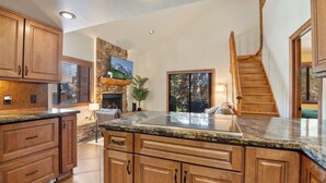 A spacious kitchen with wooden cabinets, granite countertops, and a stone fireplace. - Red Pine Condos by Park City Vacations (Park City)