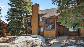 A modern two-story house with a wooden exterior, a visible staircase, and a large tree in the foreground. - Red Pine Condos by Park City Vacations (Park City)