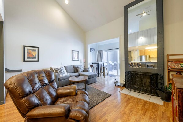 Relax in this stylish living room with a large sofa, sectional sofa, and fireplace, plus a balcony with a door.