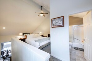 Cozy retreat with a large bed, seating area, and bathroom featuring a shower, toilet, and sink.