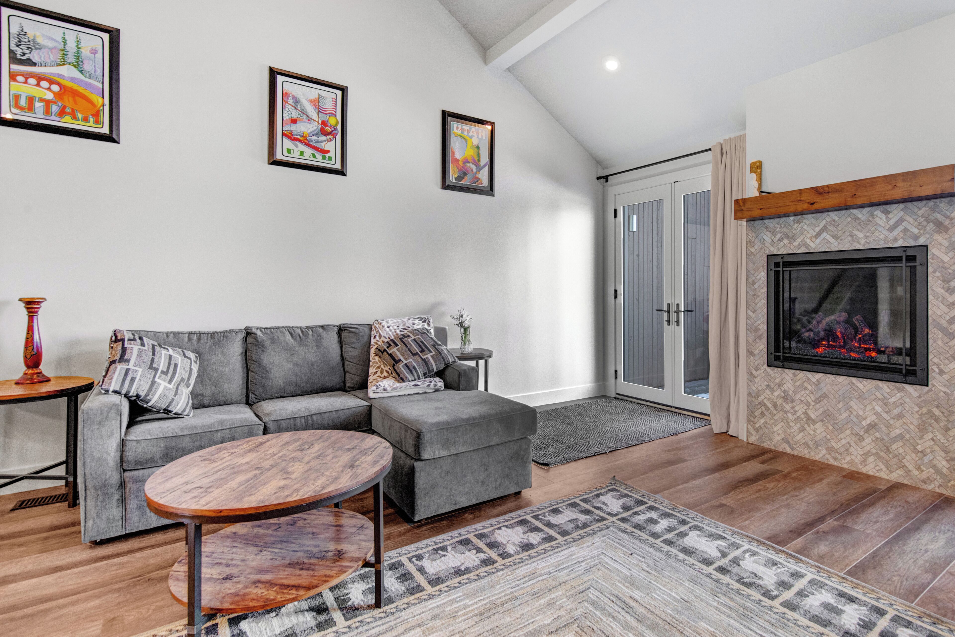 A modern living room with a gray sectional sofa, a round wooden coffee table, and a fireplace.