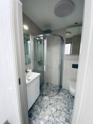 A bathroom with a glass-enclosed shower, a white sink, and a tiled floor. - AMBER Apartments `SUNNY` Studio in the city center (Morro Jable)