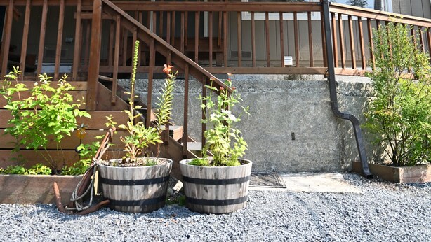 A two-story house with a wooden deck, a covered porch, and potted plants. - Comfy Duplex Unit A great for families and small groups, sleeps up to 9 (Sitka)