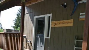 A wooden deck with steps leading to a door, a ladder, and a blue tool hanging on the wall. - Comfy Duplex Unit A great for families and small groups, sleeps up to 9 (Sitka)