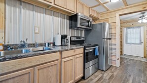 Une cuisine avec des meubles en bois, des appareils en acier inoxydable, un plan de travail en granit et un plancher en bois.