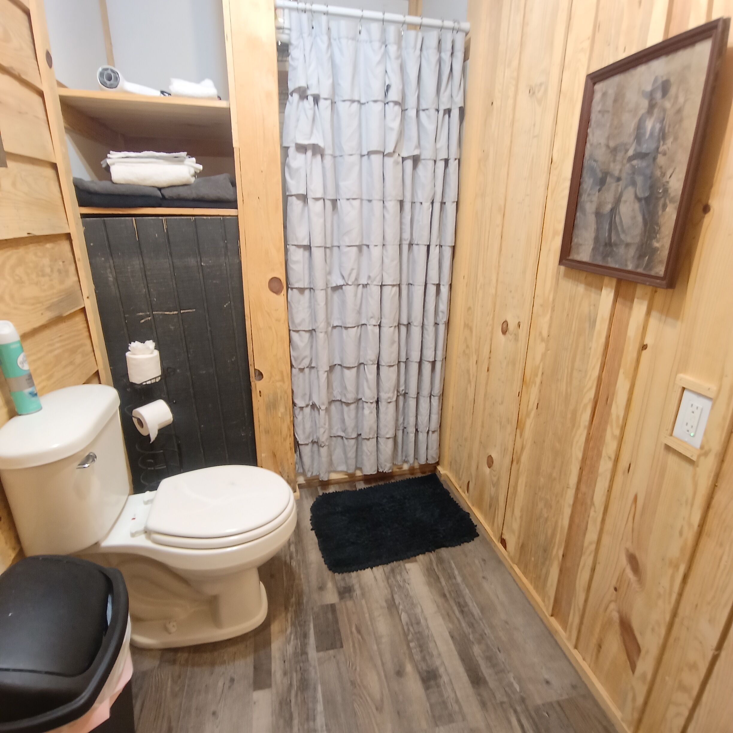 Pieni, käytännöllinen kylpyhuone, jossa on wc, pesuallas ja suihkuverho.