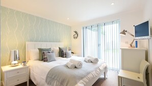 Een moderne slaapkamer met een groot bed, nachtkastjes, een bureau en een raam met jaloezieën.