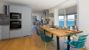 Una cocina moderna con una mesa de comedor de madera, sillas verdes y vistas al mar.