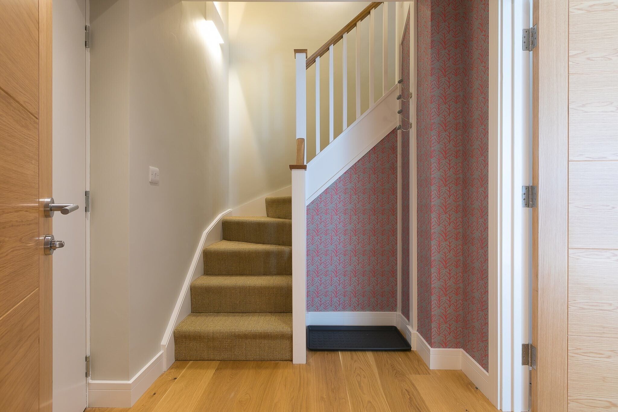 Una escalera con acabado de madera y pared con diseño rojo.