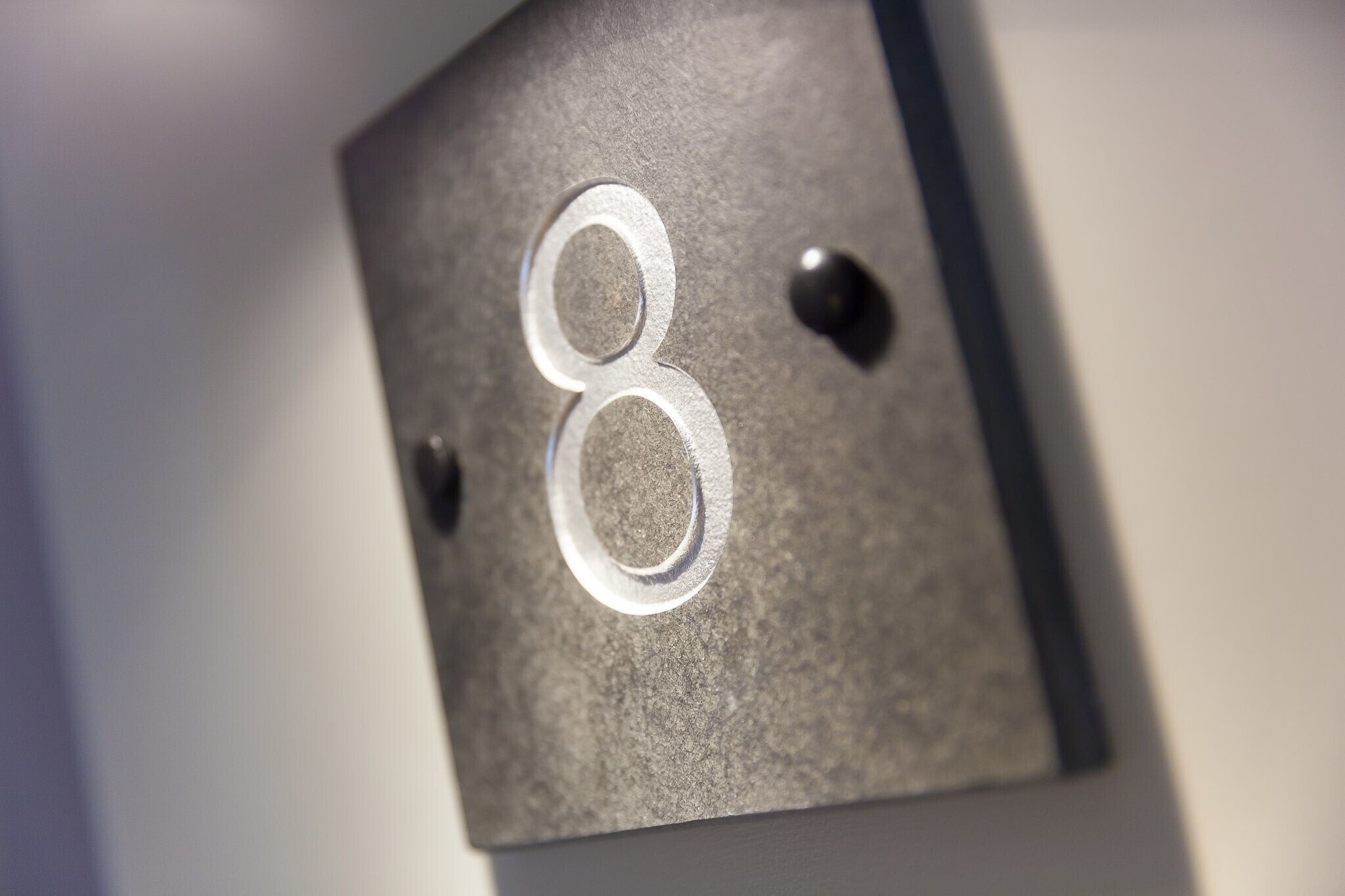 Een close-up van een metalen bord met het cijfer '8', waarschijnlijk een kamer- of sectienummer.