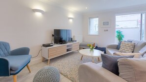 A modern living room with a TV, sofa, and coffee table. - The Sanctuary (St Ives)