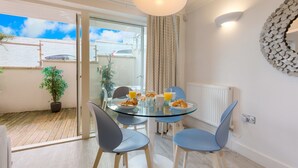 A dining area with a glass table, blue chairs, and breakfast items. - The Sanctuary (St Ives)