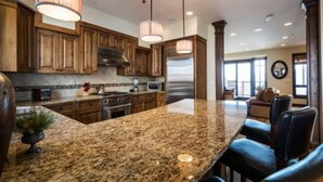 A kitchen with granite countertops, wooden cabinets, stainless steel appliances, and pendant lighting. - Fairway Springs by Park City Vacations (Park City)