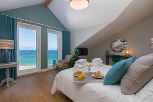 Un dormitorio con una cama grande, una bandeja de desayuno, un televisor y vista al mar.