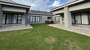 A modern building with a courtyard, large windows, and a well-maintained lawn.