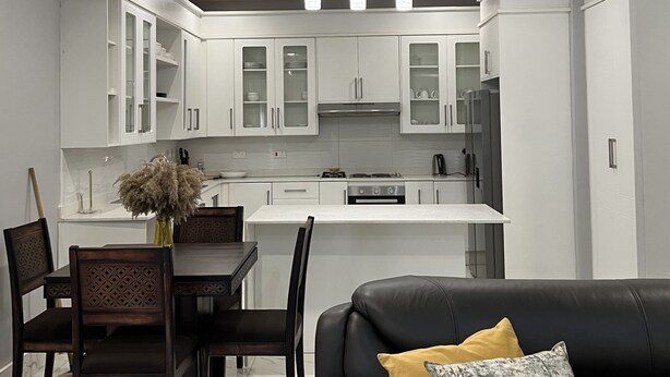 A modern kitchen with white cabinets, a central island, and pendant lighting.