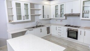 A modern kitchen with white cabinets, a stainless steel sink, a stove, and an oven.