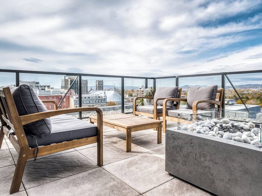 Une terrasse sur le toit, aménagée avec des meubles en bois, un foyer et offrant une vue sur la ville.