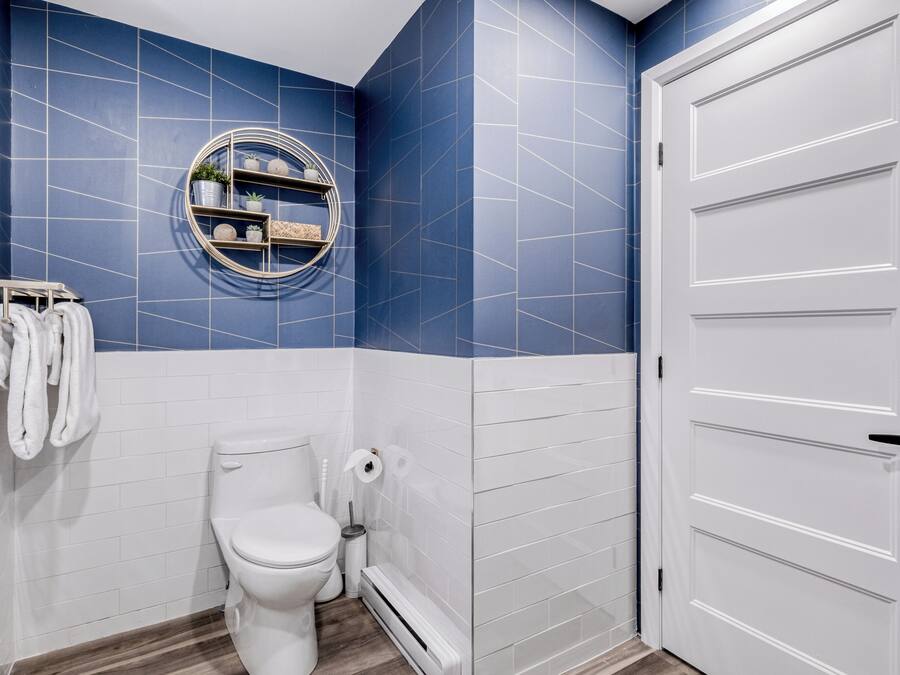 A bathroom with a white toilet, a towel rack with towels, a mirror, and a white door.