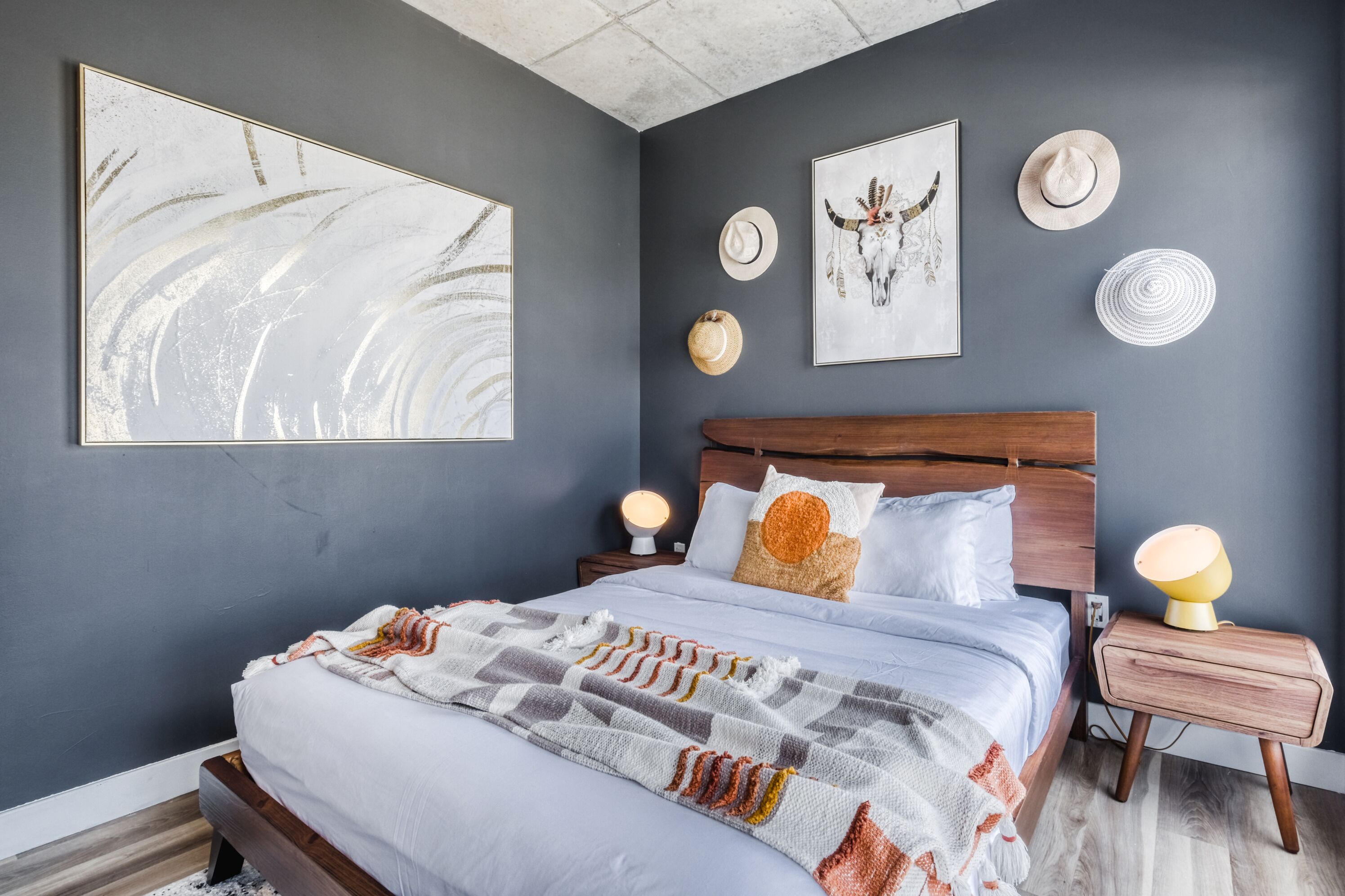 Une chambre moderne avec un grand lit, deux tables de chevet et des œuvres d’art murales.