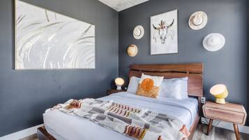 Une chambre moderne avec un grand lit, deux tables de chevet et des œuvres d’art murales.