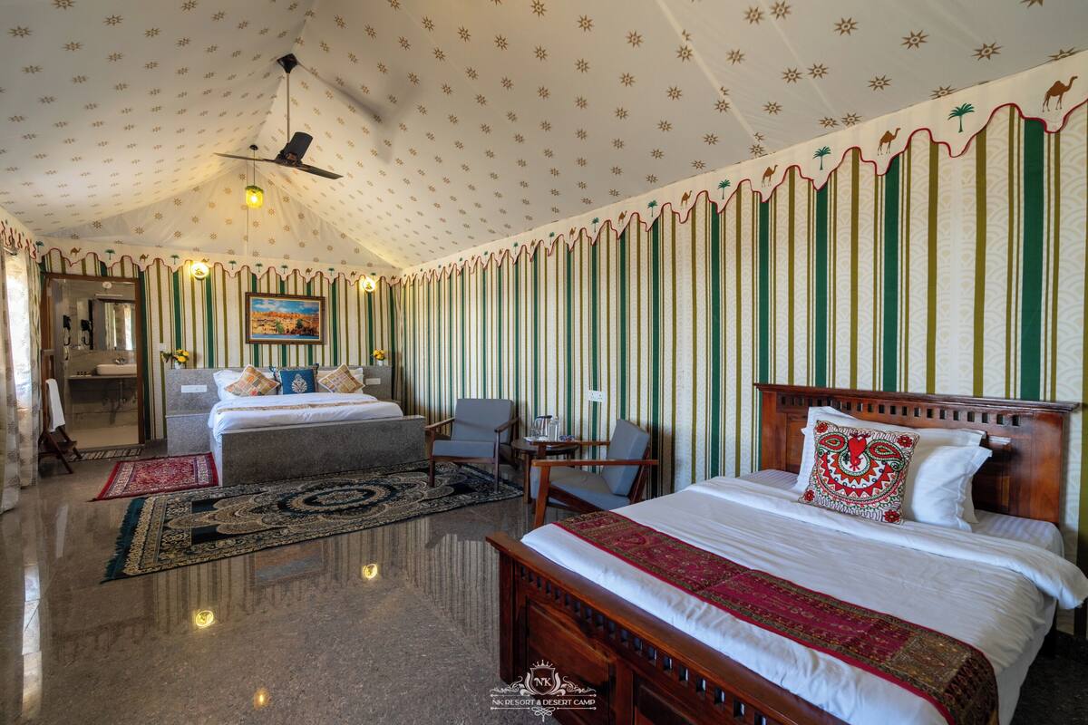 Une chambre d’hôtel avec un grand lit, deux petits lits, une tête de lit en bois, un ventilateur de plafond, un tableau et un mur à motifs.
